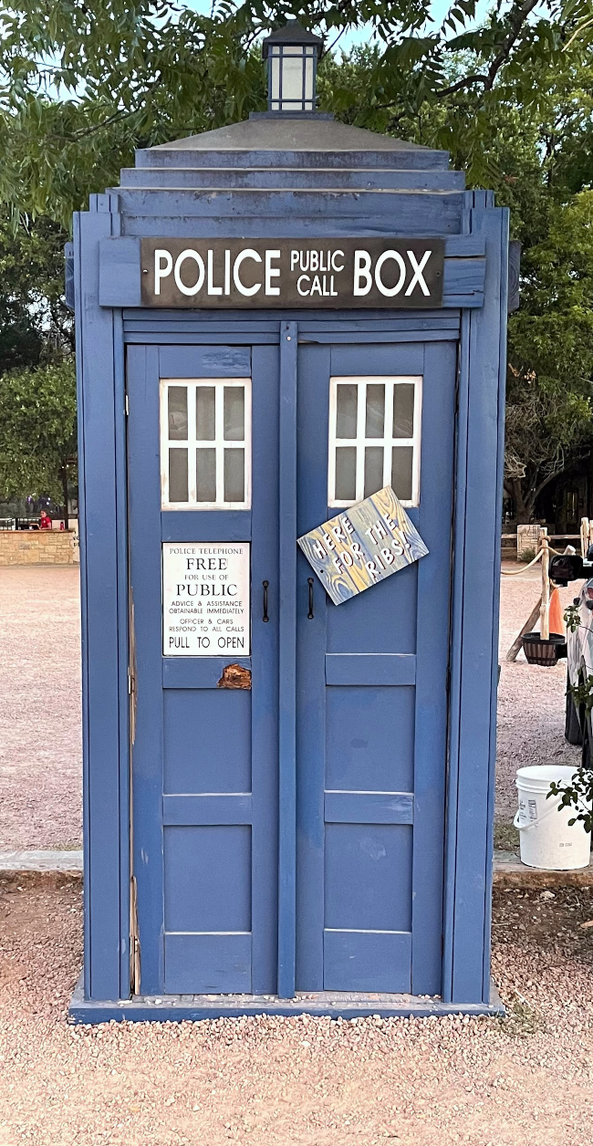 A British Police box that looks like the TARDIS from Doctor Who in the parking lot of the Salt Lick barbecue restaurant